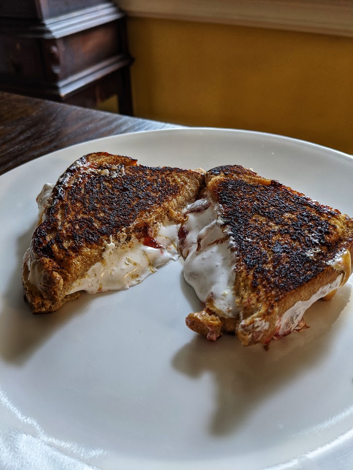Grilled fluffernutter cut in half on a white plate.