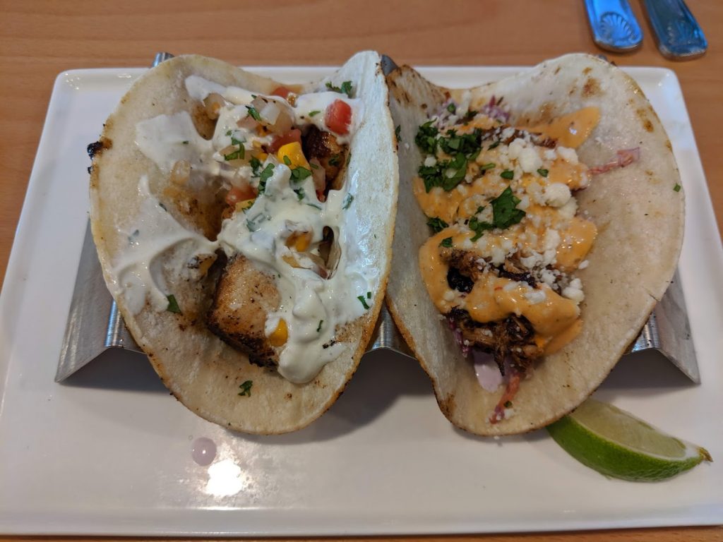 Two tacos on a metal serving rack.