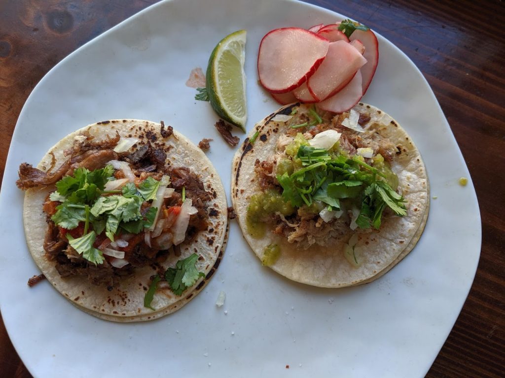 Two tacos from Tallulahs on a white plate.