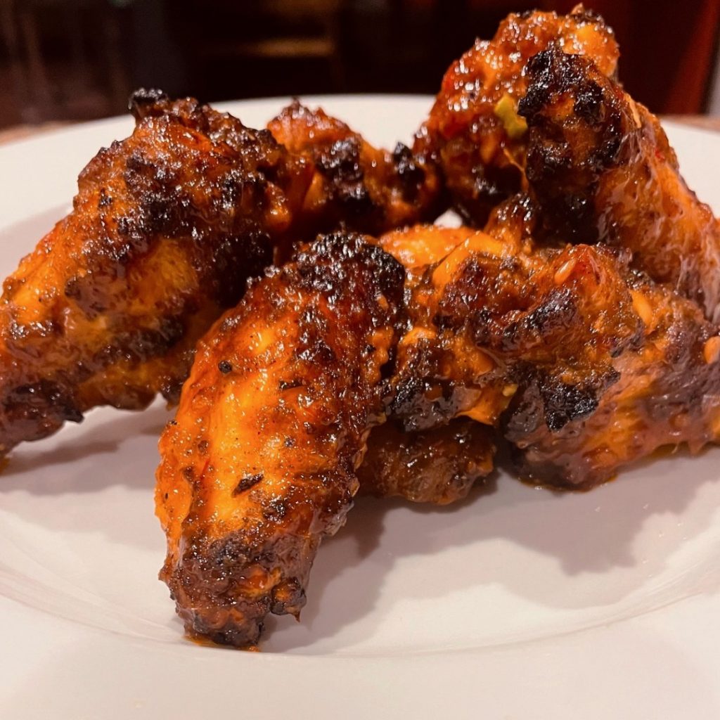 Dark cooked wings on a white plate.