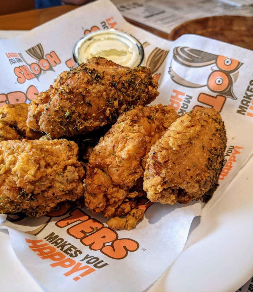 Thick battered wings on a paper lined serving dish.