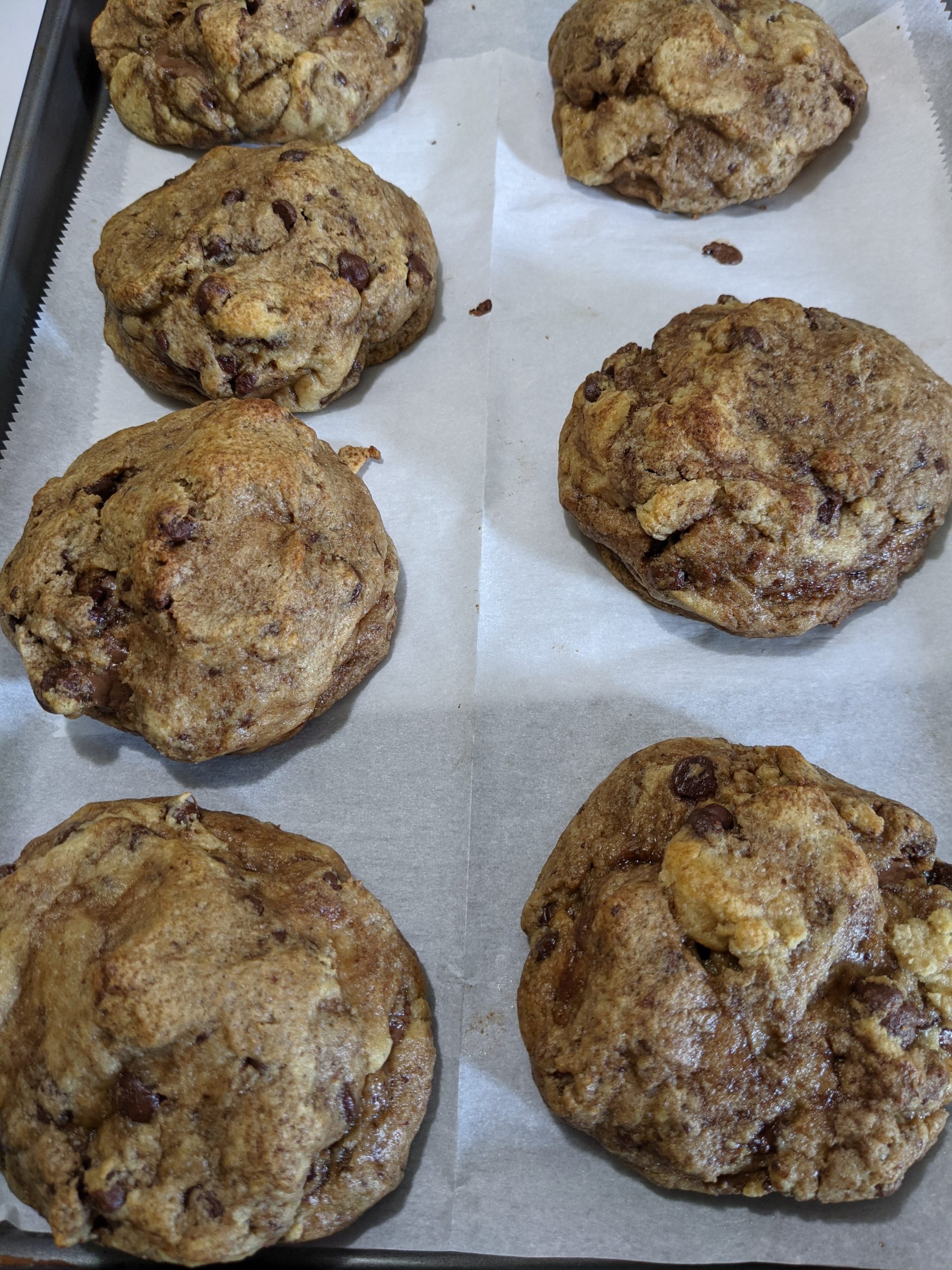 Several finished cookies fresh out of the oven sitting on a parchment lined baking sheet.