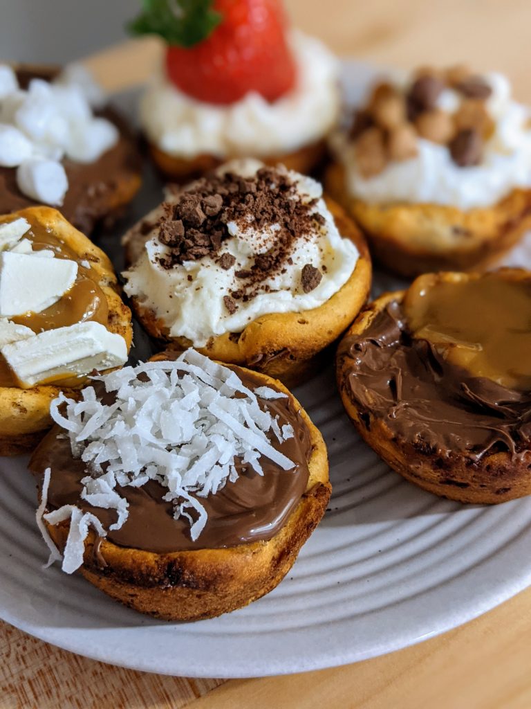 Up close picture of several plated finished cinnamon roll cups filled with various chocolates and decorations.