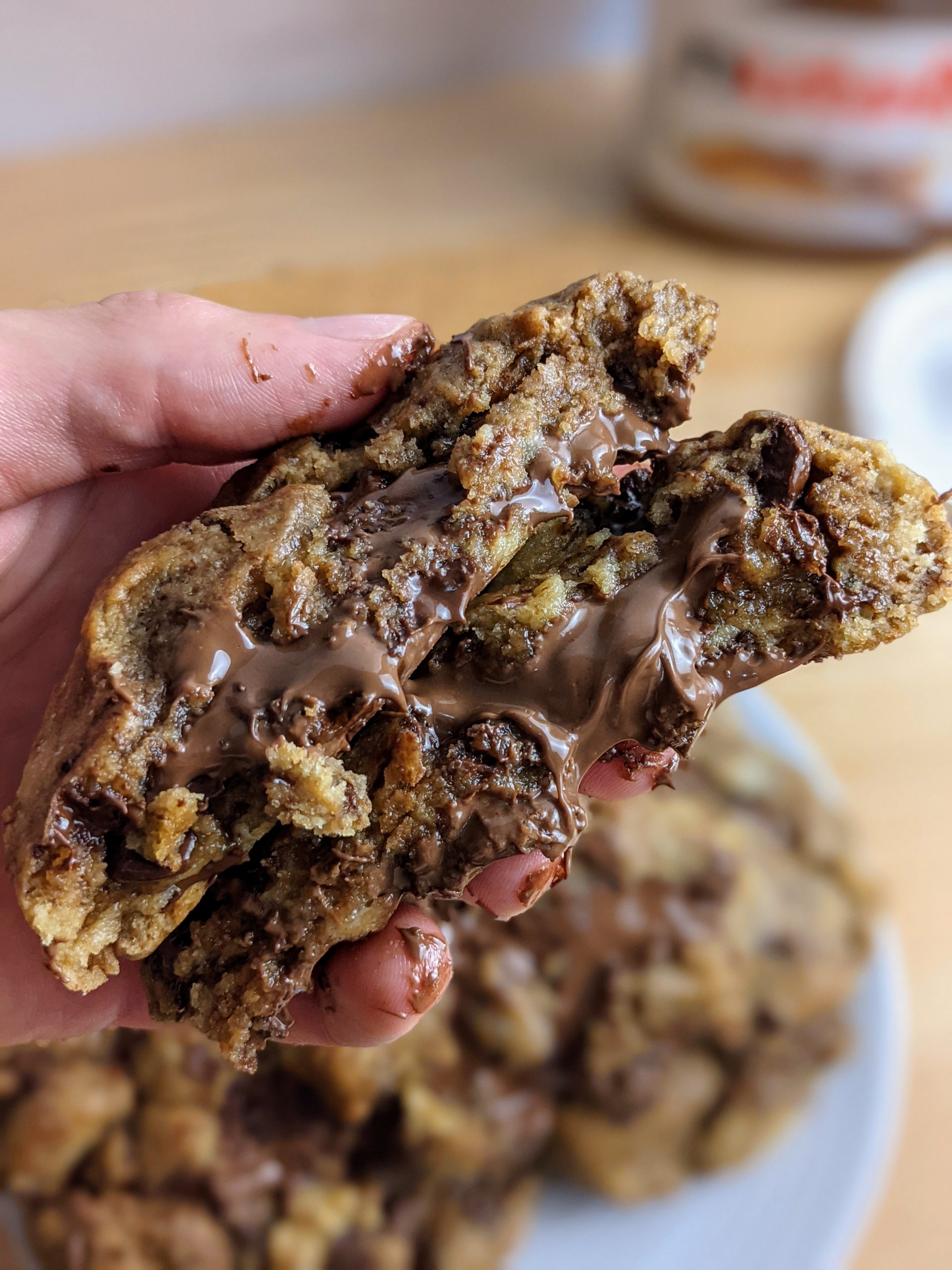 Holding a cut in half Nutella filled cookie with Nutella oozing out of the middle.