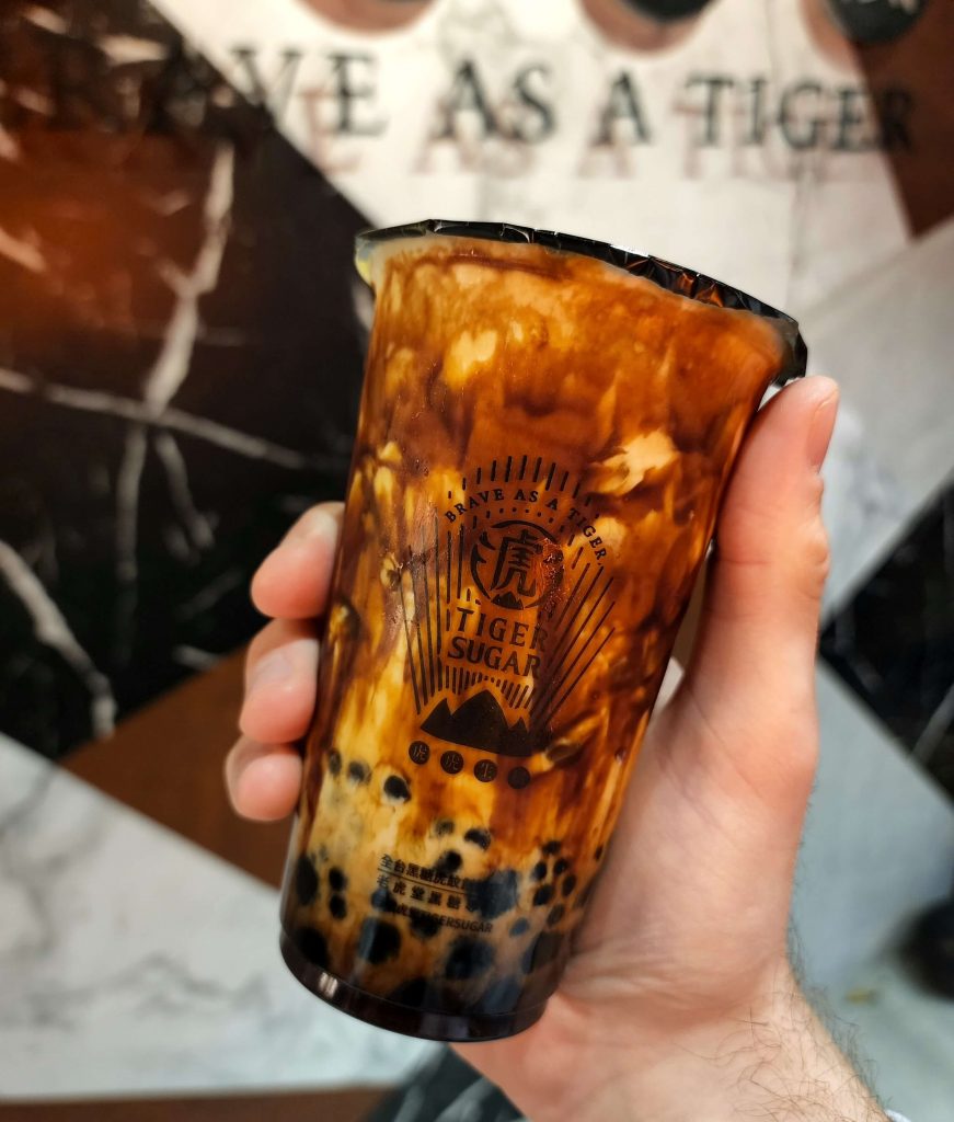 Holding a brown sugar bubble tea. Tea is a beautiful mix of brown sugar syrup and milky white tea.