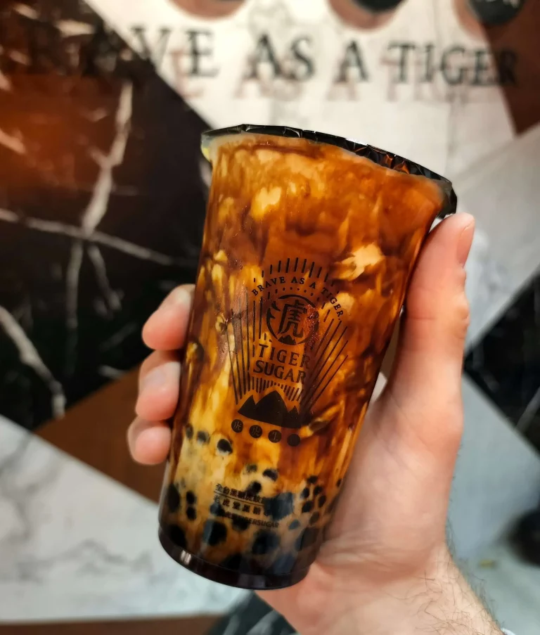 Holding a brown sugar bubble tea. Tea is a beautiful mix of brown sugar syrup and milky white tea.