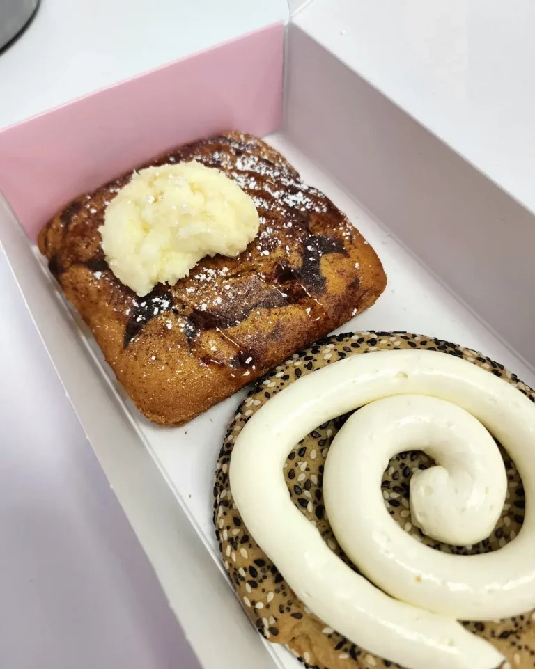French toast looking cookie which has glob of butter and syrup and powdered sugar on top. Bagel looking cookie with seeds and a swirl of white frosting,