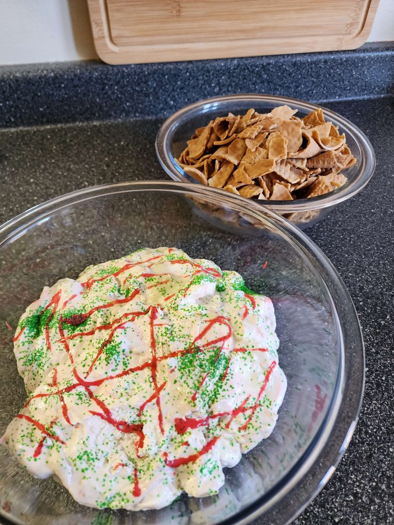 Side eye view of decorated Christmas tree dip in a glass bowl alongside pieces of sugar cones in their own glass bowl.