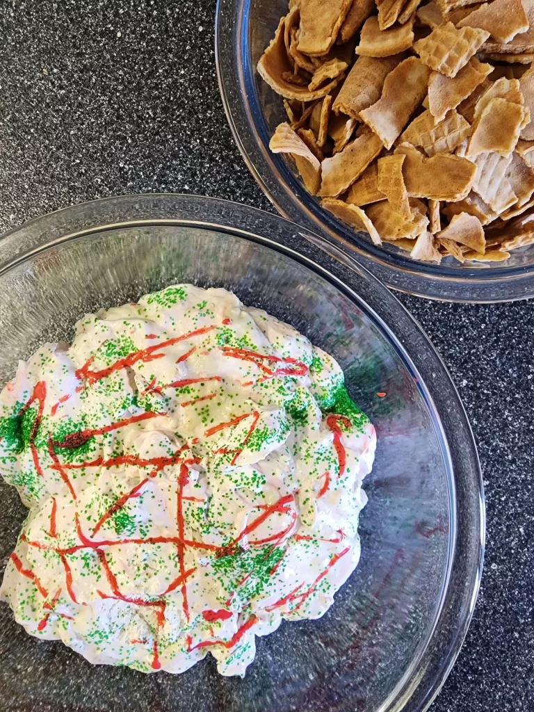 Birds eye view of decorated Christmas tree dip in a glass bowl alongside pieces of sugar cones in their own glass bowl.