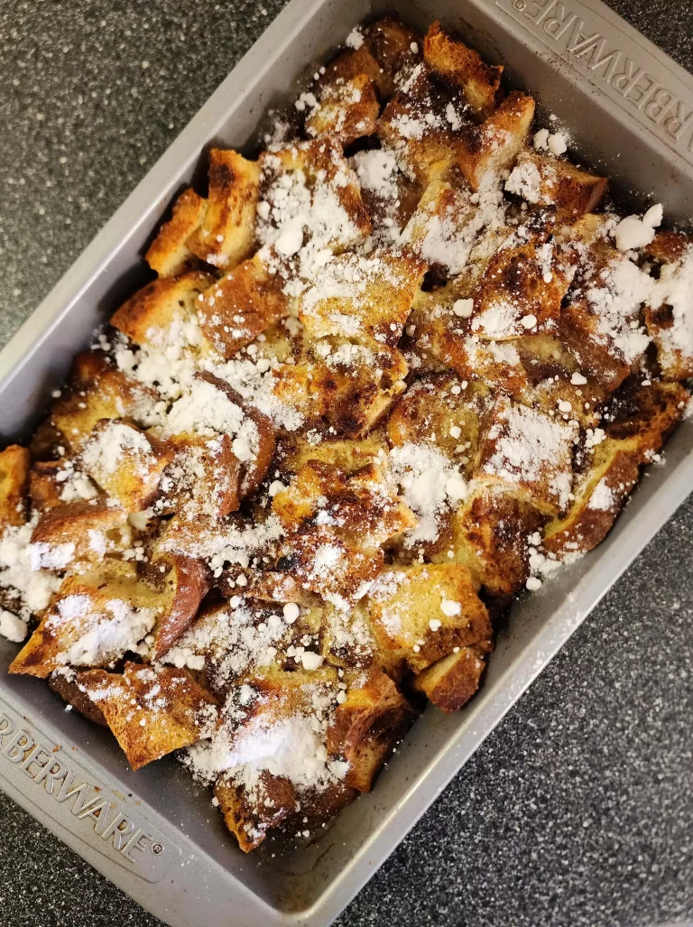 Birds eye view of baking pan with baked French toast casserole with powdered sugar on top.