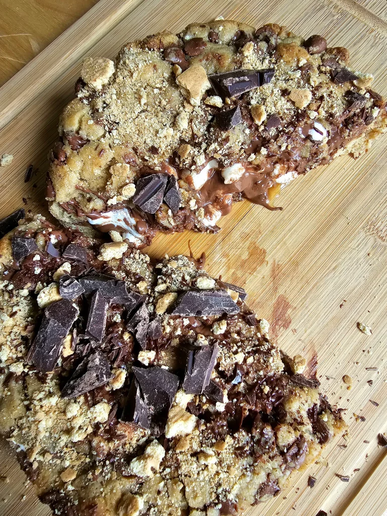 Stuffed cookie cut in half and separated on wooden cutting board, chocolate and marshmallow ooze out.