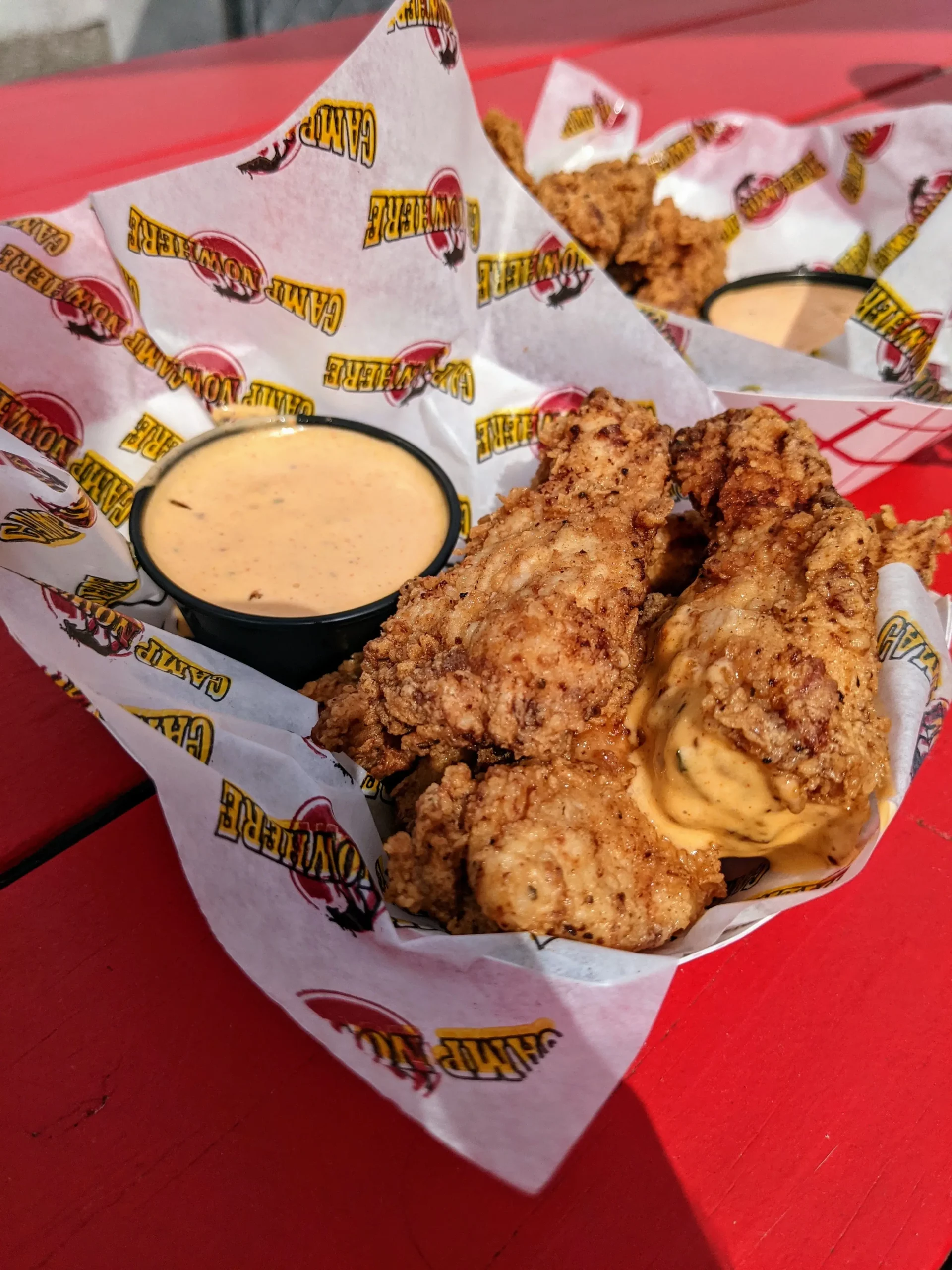 Camp Nowhere chicken wings and sauce on a table.
