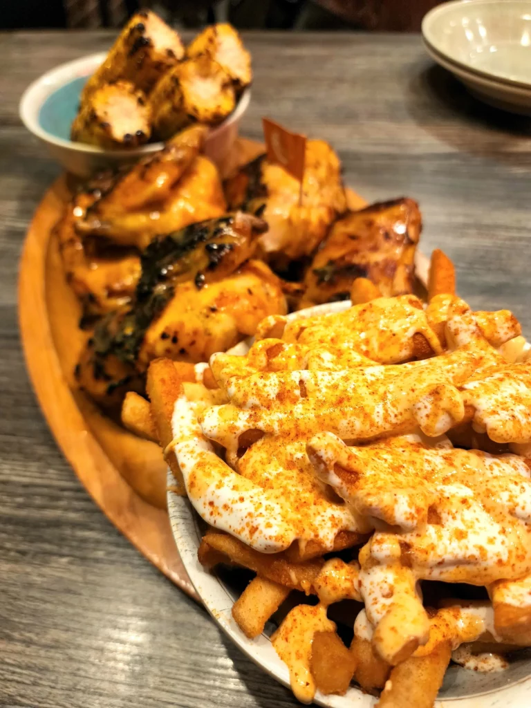 Rhode Island Providence's Thayer Street's Tribos Peri Peri chicken, fries, and corn on a wooden plate.
