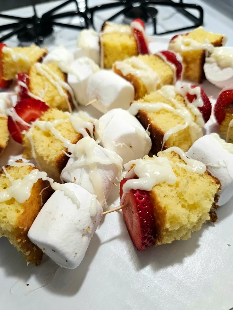 Several Marshmallow Strawberry Shortcake Kabobs on a large white plate.