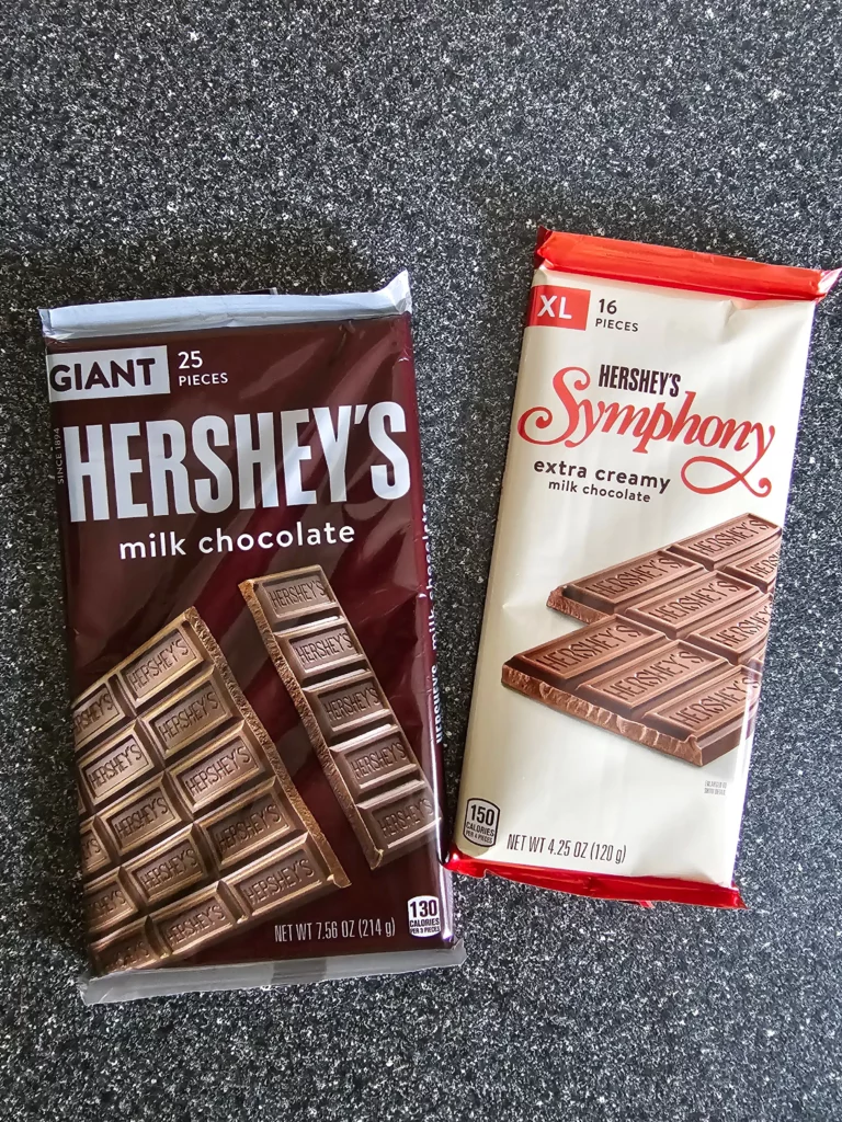 Package of Hershey's Symphony XL Extra Creamy Milk Chocolate bar next to a package of Giant Hershey's Milk Chocolate bar.