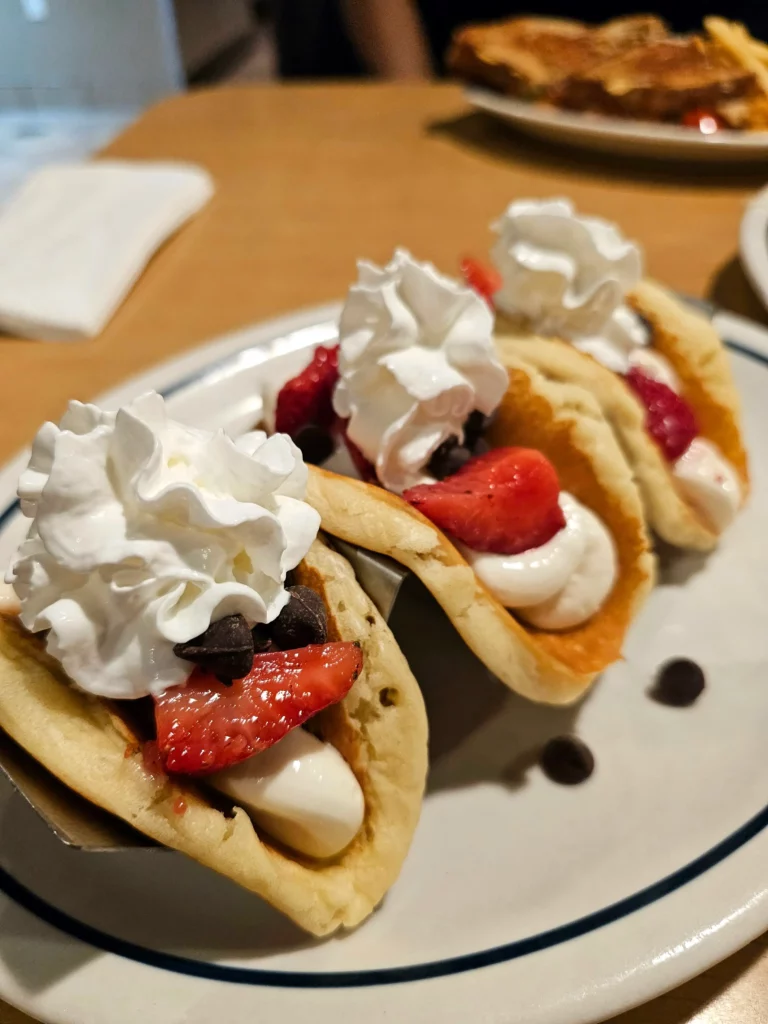 Three IHOP Pancake Strawberry Cheesecake Tacos lined up on a plat.