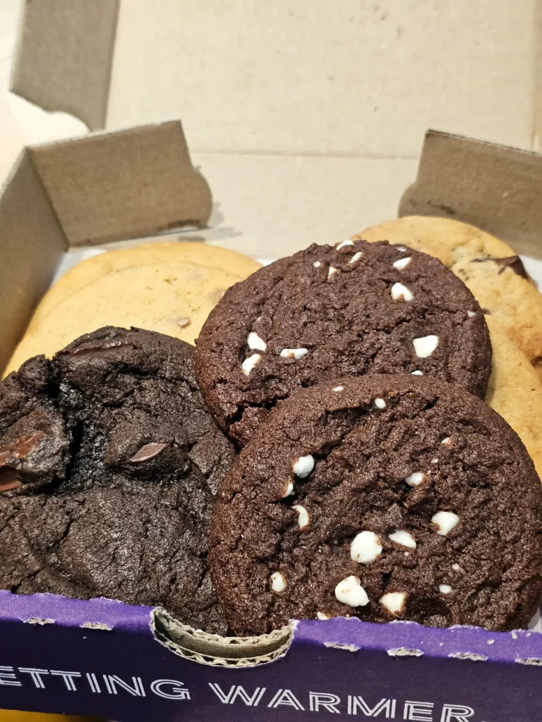 Several Insomnia Cookies in a box including 2023 Limited Edition Vegan White Chocolate Cold Brew Latte and French Toast.