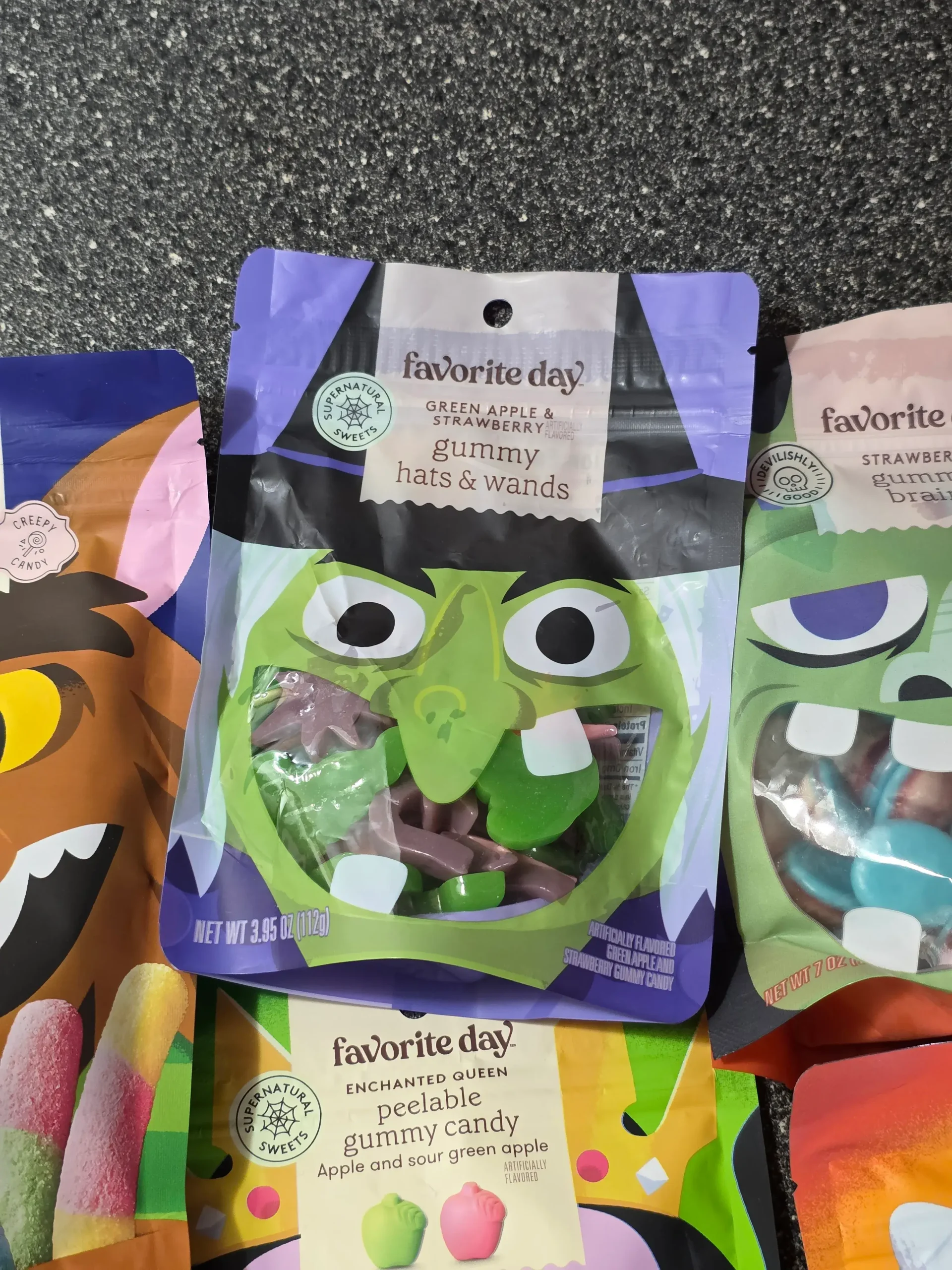 Target Favorite Day Halloween Gummy Candy: Enchanted Queen Peelable Apple & Sour Green Apple, Witch Hats and Wands, Halloween Monster Bash Peelable Fruity, Strawberry Gummy Candy Brains, and Fruity Sour Freeze-Dried Candy Worms.