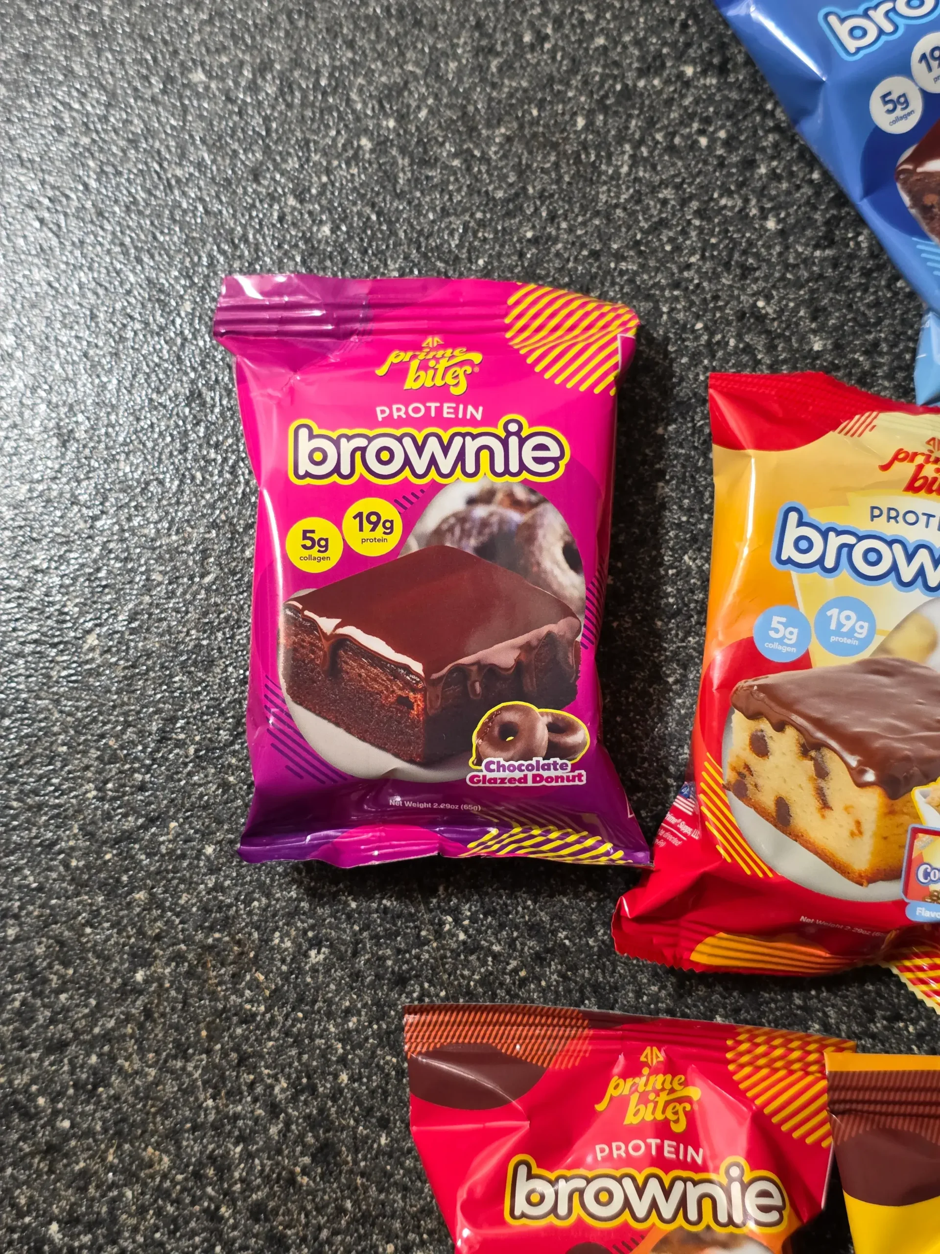Prime Bites variety pack, including: Chocolate Glazed Donut, Glazed Cinnamon Roll, Birthday Cake, Banana Nut, Peanut Butter Candy Crunch, Chocolate Cookie Monster, Cookie Dough, Blueberry Cobbler, and Cookies & Cream Blondie.