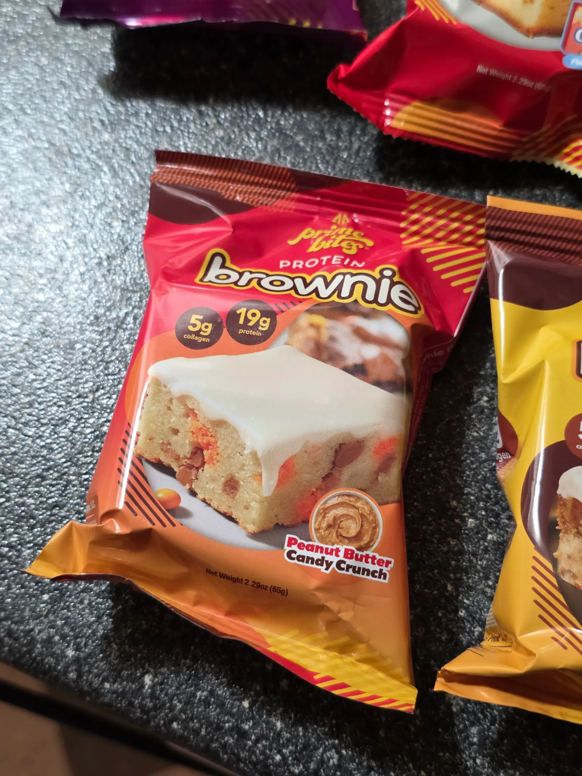 Prime Bites variety pack, including: Chocolate Glazed Donut, Glazed Cinnamon Roll, Birthday Cake, Banana Nut, Peanut Butter Candy Crunch, Chocolate Cookie Monster, Cookie Dough, Blueberry Cobbler, and Cookies & Cream Blondie.