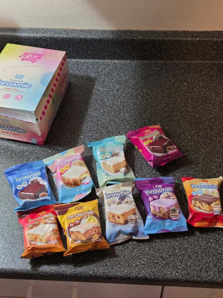 Prime Bites variety pack, including: Chocolate Glazed Donut, Glazed Cinnamon Roll, Birthday Cake, Banana Nut, Peanut Butter Candy Crunch, Chocolate Cookie Monster, Cookie Dough, Blueberry Cobbler, and Cookies & Cream Blondie.