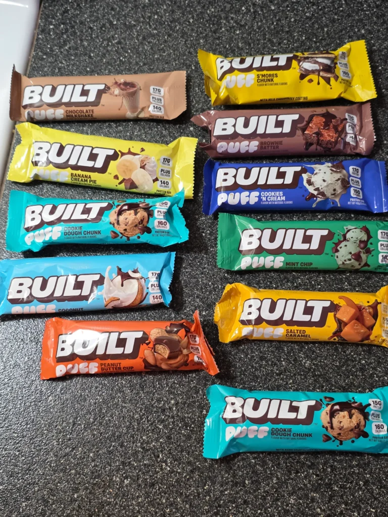 Built Puff Protein Bars: Chocolate Milkshake, Banana Cream Pie, Cookie Dough Chunk, Coconut, Peanut Butter Cup, S'mores Chunk, Brownie Batter, Cookies 'N Cream, Mint Chip, Salted Caramel, and Cookie Dough Chunk.