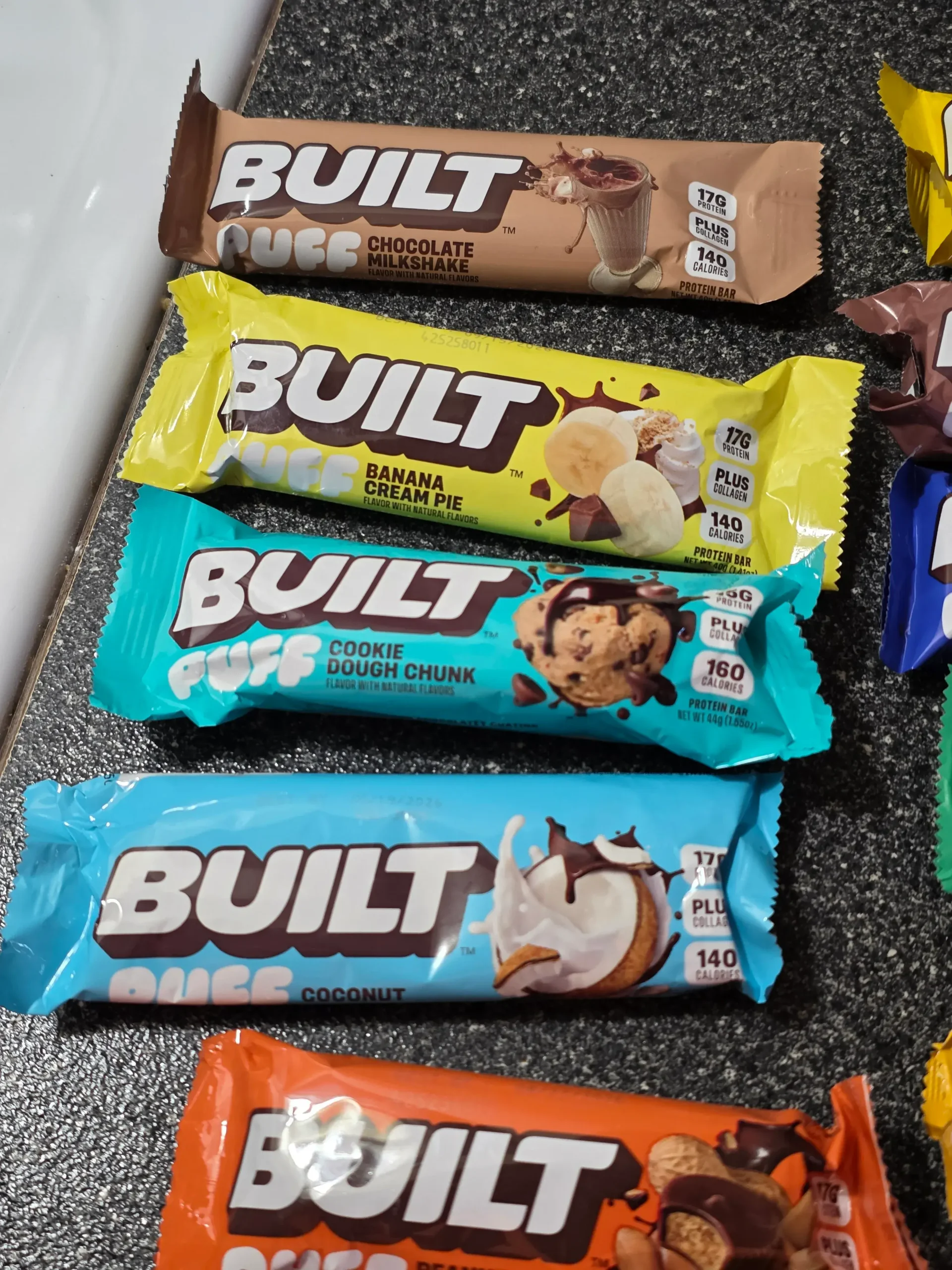 Built Puff Protein Bars: Chocolate Milkshake, Banana Cream Pie, Cookie Dough Chunk, Coconut, Peanut Butter Cup, S'mores Chunk, Brownie Batter, Cookies 'N Cream, Mint Chip, Salted Caramel, and Cookie Dough Chunk.