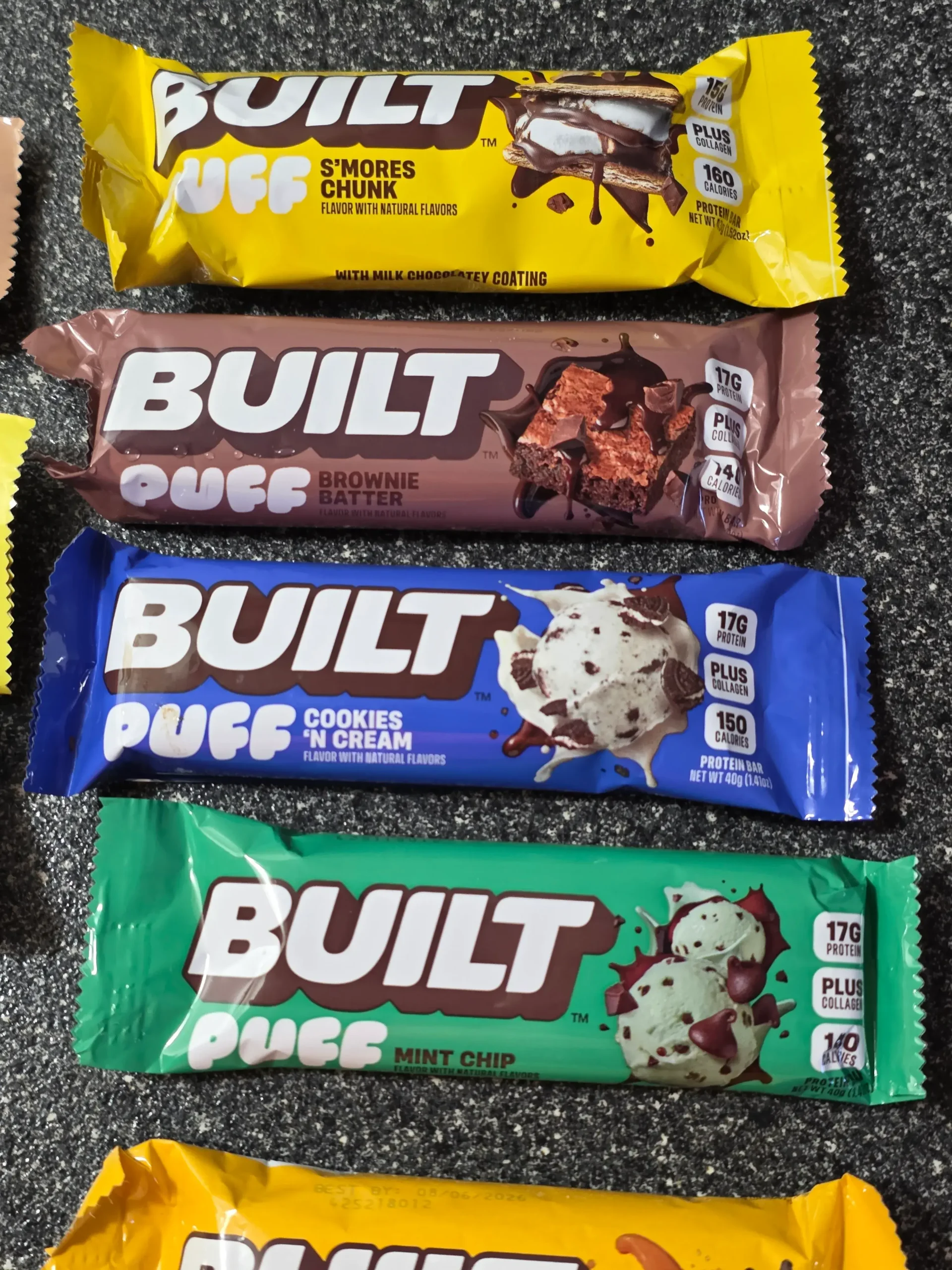 Built Puff Protein Bars: Chocolate Milkshake, Banana Cream Pie, Cookie Dough Chunk, Coconut, Peanut Butter Cup, S'mores Chunk, Brownie Batter, Cookies 'N Cream, Mint Chip, Salted Caramel, and Cookie Dough Chunk.