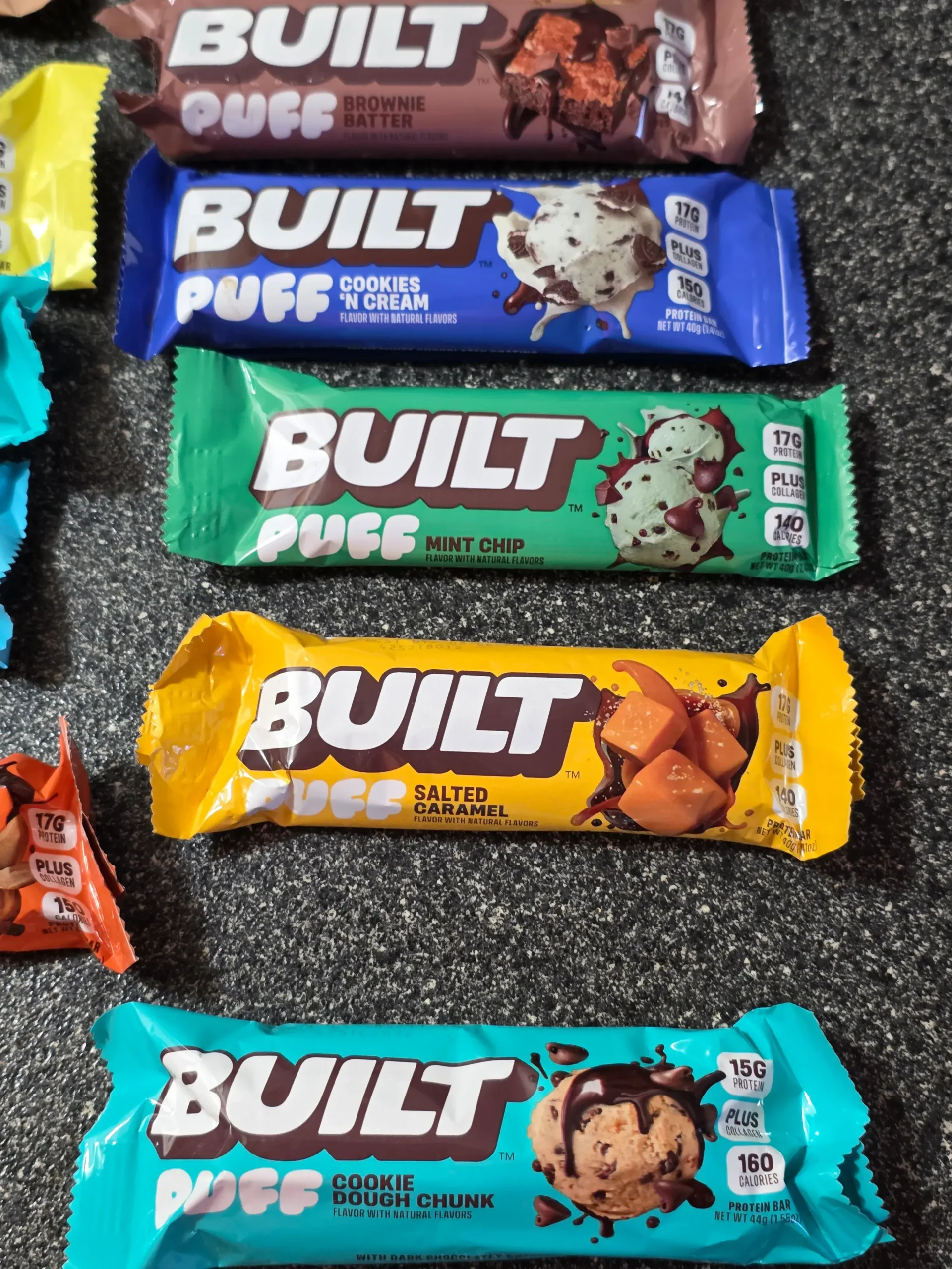 Built Puff Protein Bars: Chocolate Milkshake, Banana Cream Pie, Cookie Dough Chunk, Coconut, Peanut Butter Cup, S'mores Chunk, Brownie Batter, Cookies 'N Cream, Mint Chip, Salted Caramel, and Cookie Dough Chunk.
