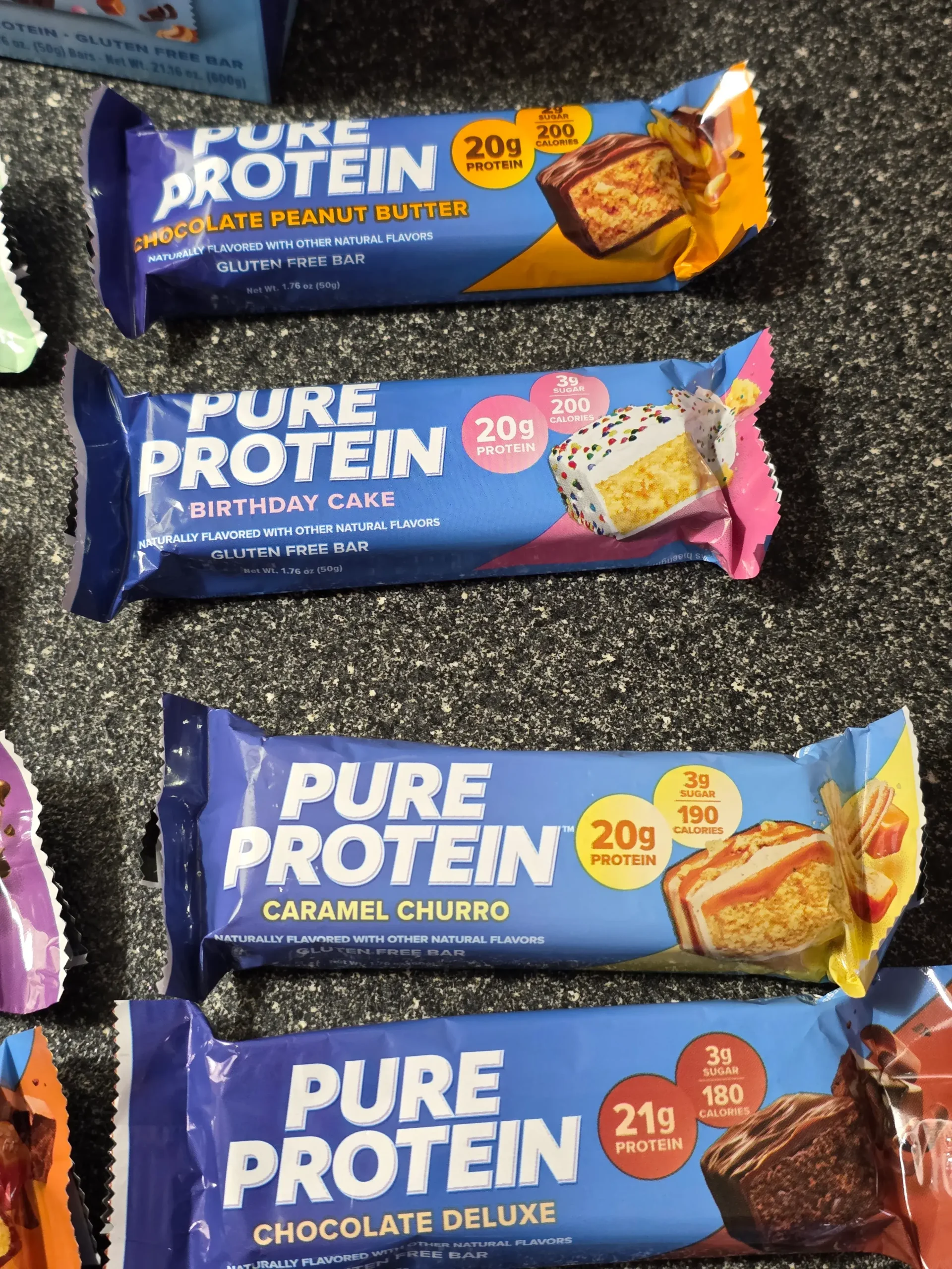 Pure Protein Bar Variety Pack: Chocolate Peanut Butter, Birthday Cake, Caramel Churro, Chocolate Deluxe, Sundae Cone, Cookies & Cream, Galactic Brownie, Brookie, Chocolate Salted Caramel, Chewy Chocolate Chip, Lemon Cake, and Chocolate Mint Cookie.