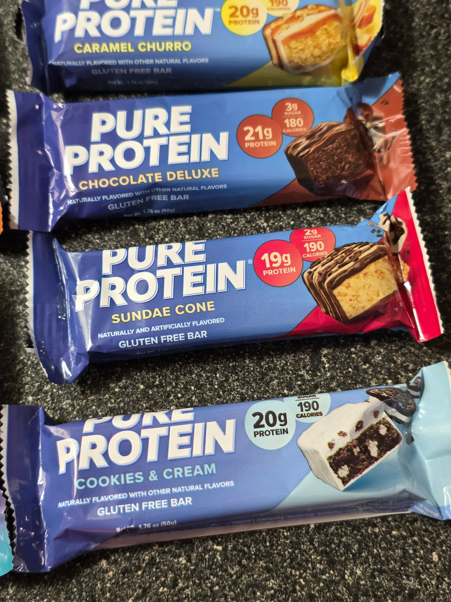 Pure Protein Bar Variety Pack: Chocolate Peanut Butter, Birthday Cake, Caramel Churro, Chocolate Deluxe, Sundae Cone, Cookies & Cream, Galactic Brownie, Brookie, Chocolate Salted Caramel, Chewy Chocolate Chip, Lemon Cake, and Chocolate Mint Cookie.