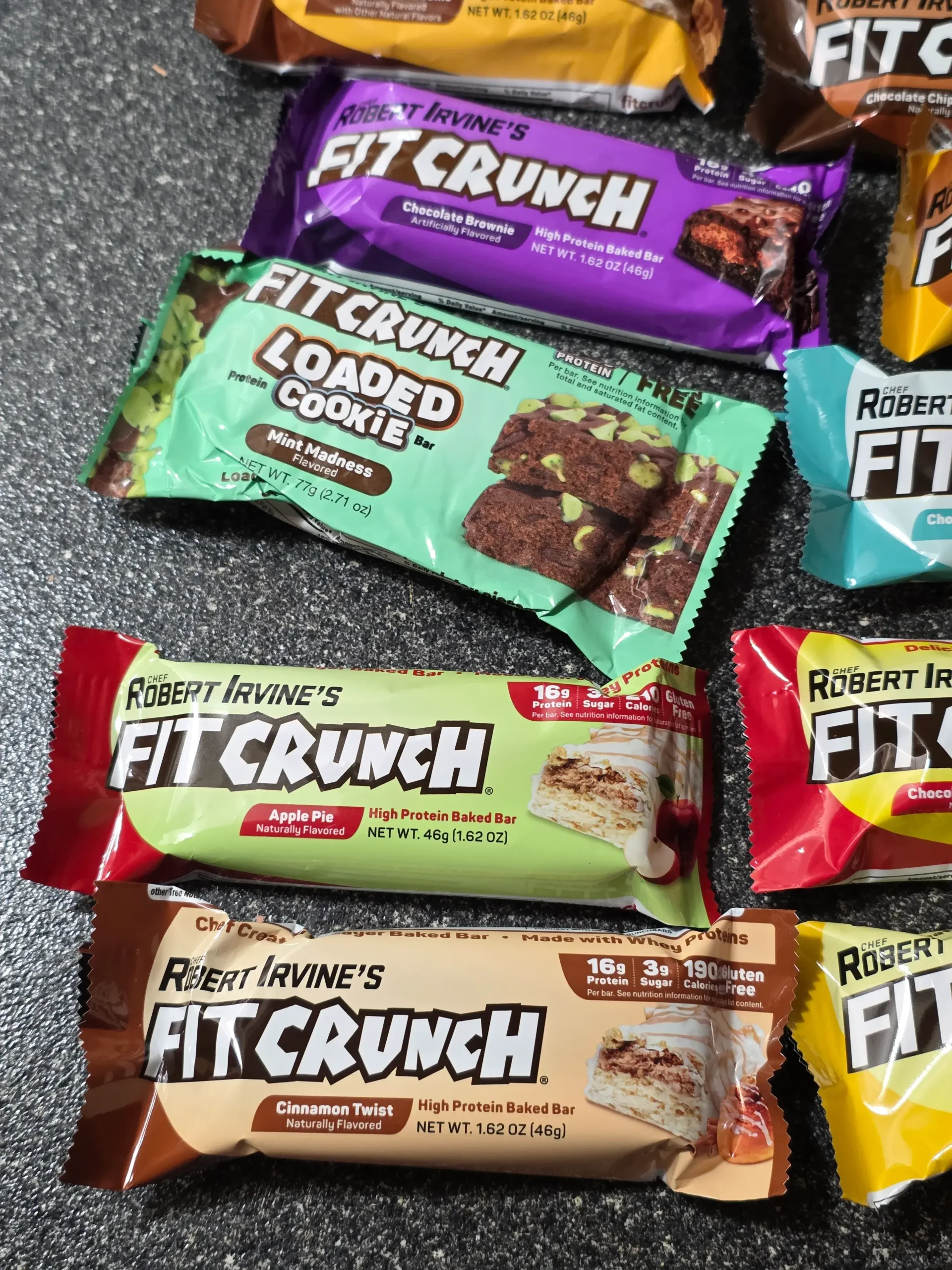 Robert Irvine's FITCRUNCH Protein Bars, including Flavor Lover's Variety pack: Chocolate Peanut Butter, Chocolate Banana, Chocolate Chip Cookie Dough, Chocolate Brownie, Chocolate Coconut Almond, Cinnamon Twist, Milk & Cookies, Lemon Cake, Apple Pie, and Mint Madness Loaded Cookie.
