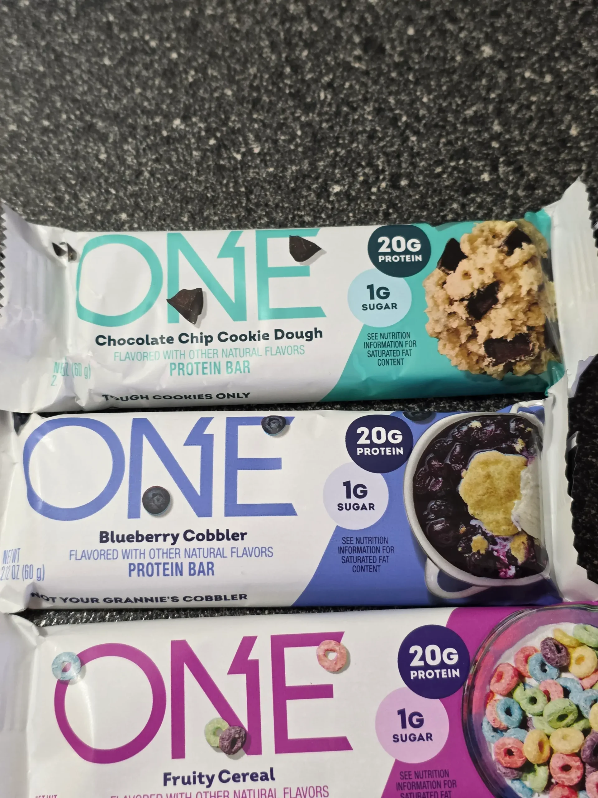 ONE Protein Bar Variety Sample Pack: Maple Glazed Doughnut, Lemon Cake, Cinnamon Roll, S'mores, Chocolate Almond Bliss, Chocolate Chip Cookie Dough, Blueberry Cobbler, Fruity Cereal, Lemon Cake, and Peanut Butter Cup.