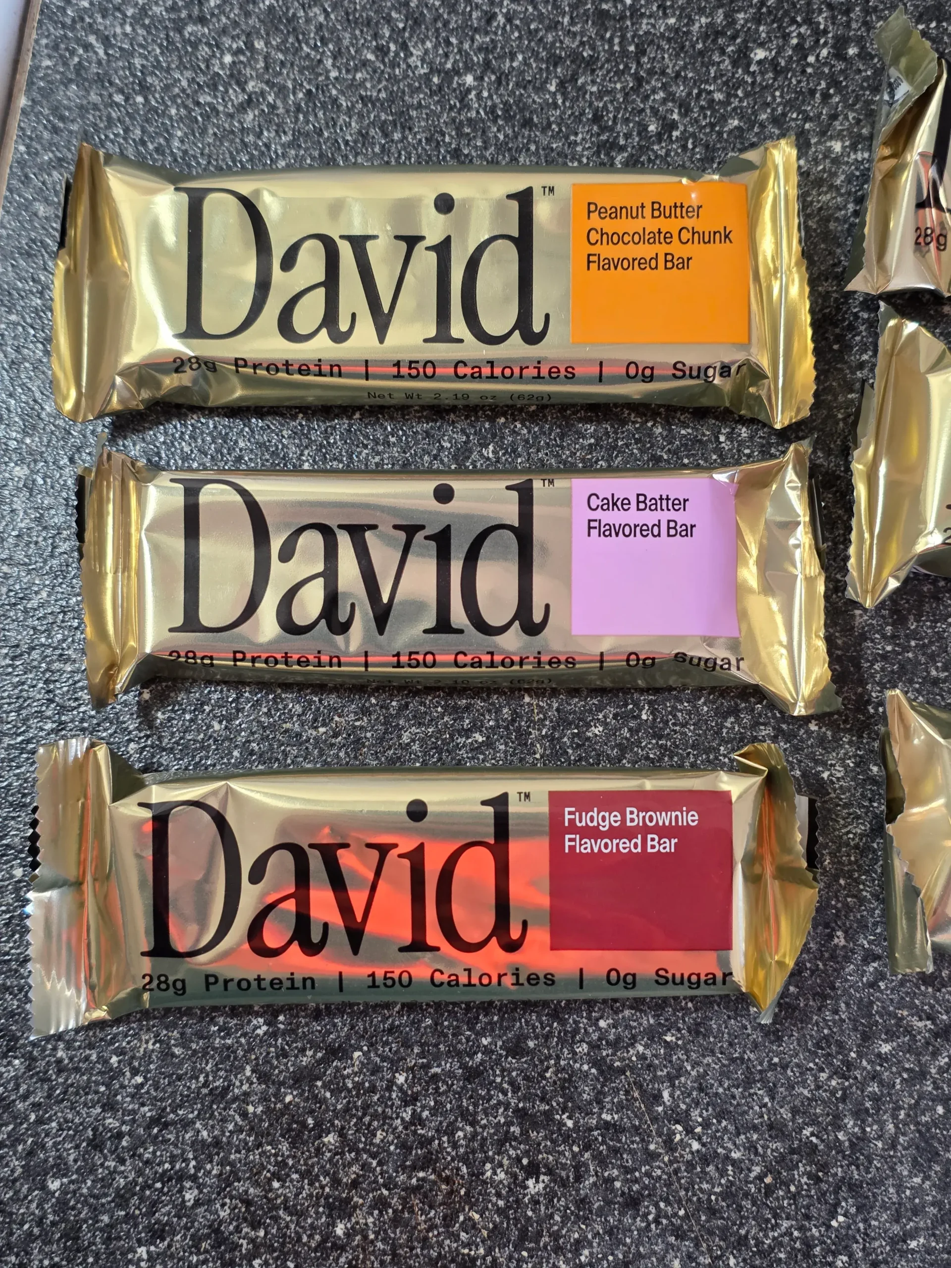 David Protein Bar: Cinnamon Roll, Red Velvet, Fudge Brownie, Cake Batter, Peanut Butter Chocolate Chunk,  Chocolate Chip Cookie Dough, Salted Peanut Butter, and Blueberry Pie.