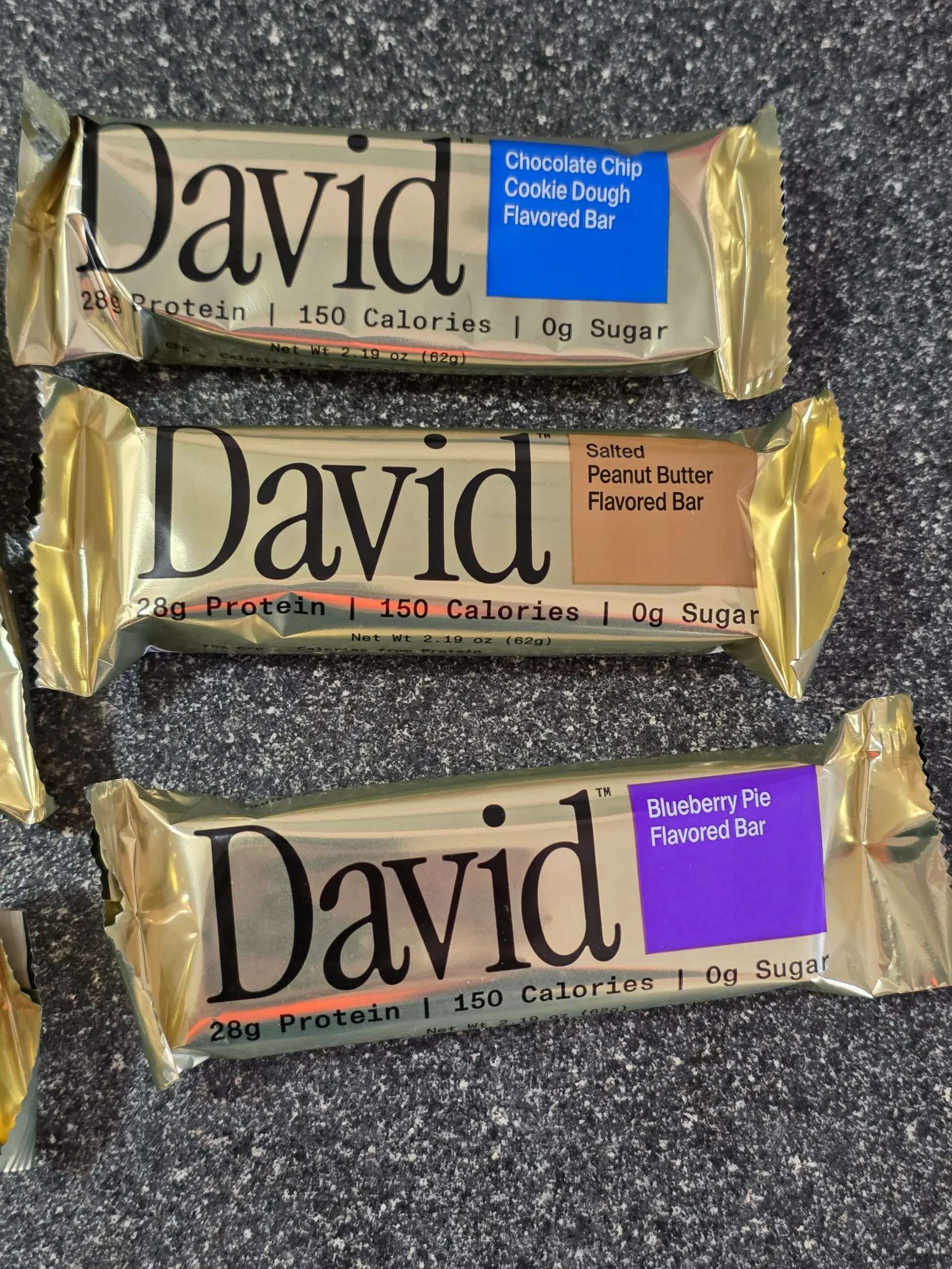 David Protein Bar: Cinnamon Roll, Red Velvet, Fudge Brownie, Cake Batter, Peanut Butter Chocolate Chunk,  Chocolate Chip Cookie Dough, Salted Peanut Butter, and Blueberry Pie.